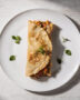 A beautifully plated savory crepe recipe with golden edges, oozing with cheese and béchamel sauce.