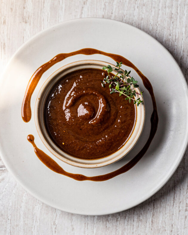 A vibrant green skirt steak sauce drizzled over perfectly grilled steak on a rustic wooden board.
