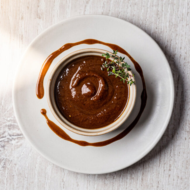 A vibrant green skirt steak sauce drizzled over perfectly grilled steak on a rustic wooden board.