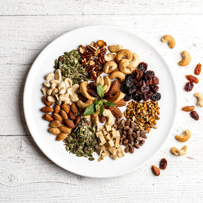 A vibrant, crunchy homemade snacks mix overflowing from a rustic wooden bowl.