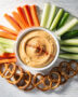 A creamy honey-mustard dip in a white bowl, surrounded by soft pretzels, perfect for quick snacks treats.