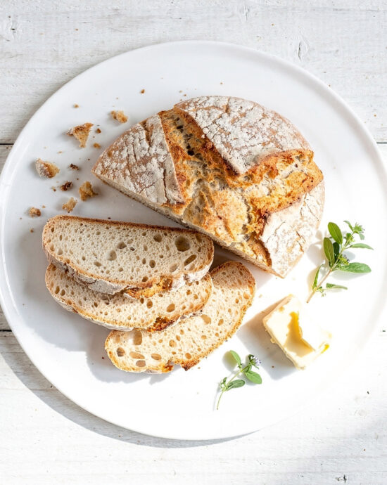 A rustic loaf of soda bread with buttermilk recipe sits on a wooden cutting board, warm from the oven.