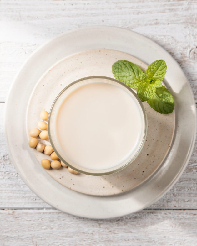 A creamy, homemade soya drink in a simple ceramic cup, resting on a rustic wooden table.