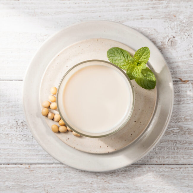 A creamy, homemade soya drink in a simple ceramic cup, resting on a rustic wooden table.