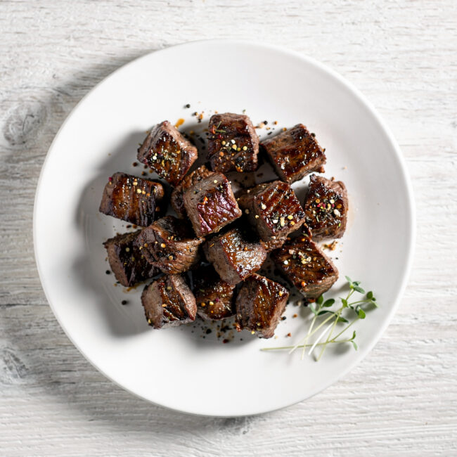 A close-up shot of savory steak bites coated in a rich, dark steak bites seasoning, ready to be seared.