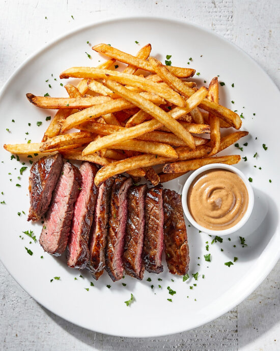 A perfectly seared steak and crispy fries drizzled with a rich, savory steak frites recipe sauce.