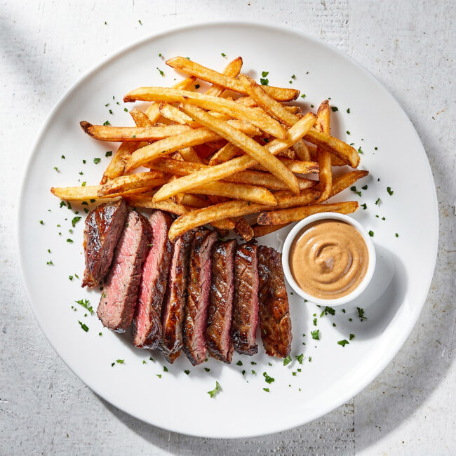 A perfectly seared steak and crispy fries drizzled with a rich, savory steak frites recipe sauce.