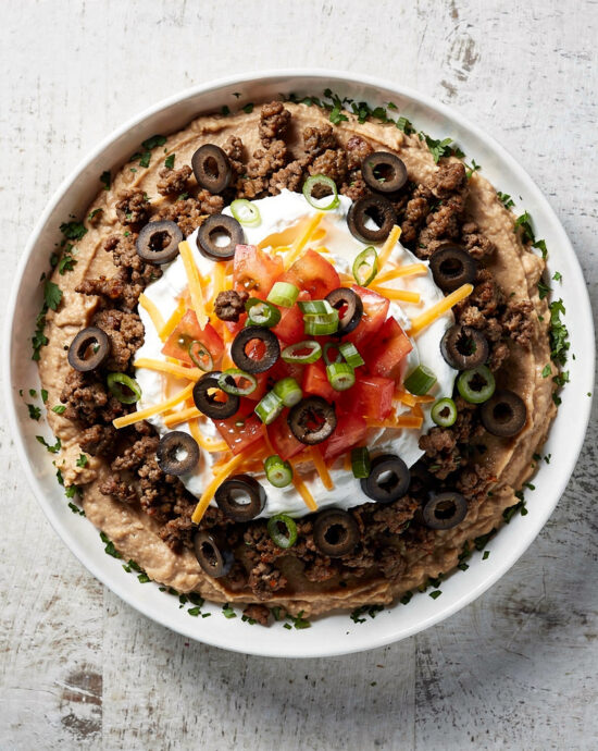 A colorful and inviting taco dip served in a rustic dish, ready for scooping.