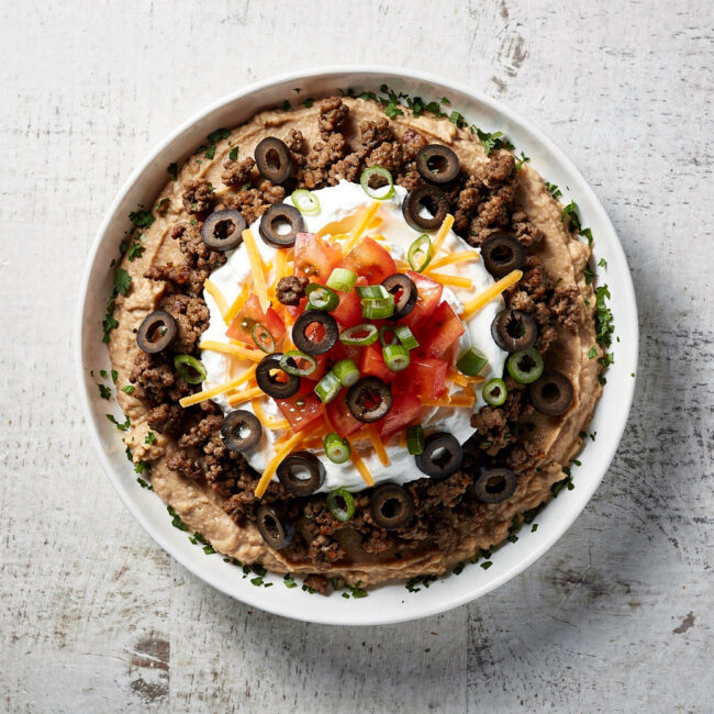 A colorful and inviting taco dip served in a rustic dish, ready for scooping.