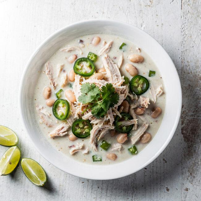 A creamy and comforting bowl of white chicken chili recipe, garnished with lime and cilantro.