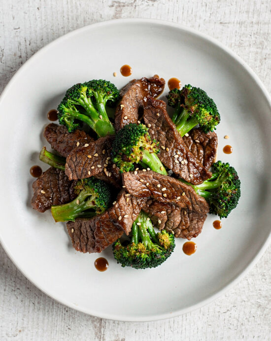 A steaming plate of the classic beef and broccoli recipe, featuring tender slices of beef and crisp broccoli in a glossy, savory sauce.