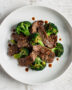 A steaming plate of the classic beef and broccoli recipe, featuring tender slices of beef and crisp broccoli in a glossy, savory sauce.