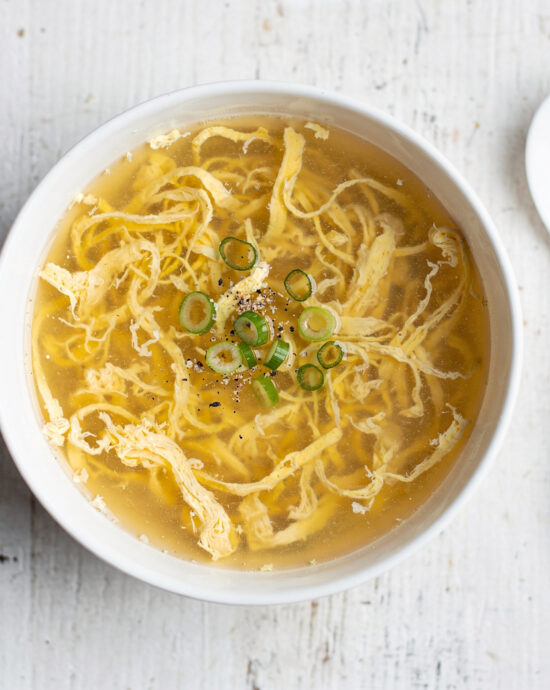 A perfectly executed egg drop soup recipe, featuring silky egg ribbons in a clear, savory broth, garnished with scallions.
