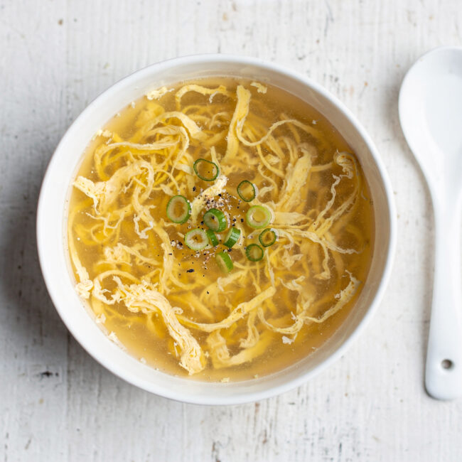 A perfectly executed egg drop soup recipe, featuring silky egg ribbons in a clear, savory broth, garnished with scallions.