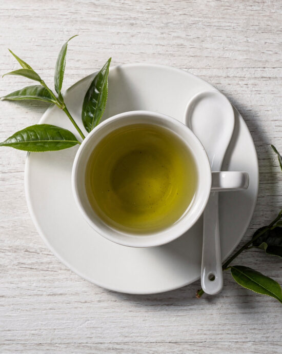 A jar of green tea chinese paste sits next to fresh ingredients on a rustic wooden table.