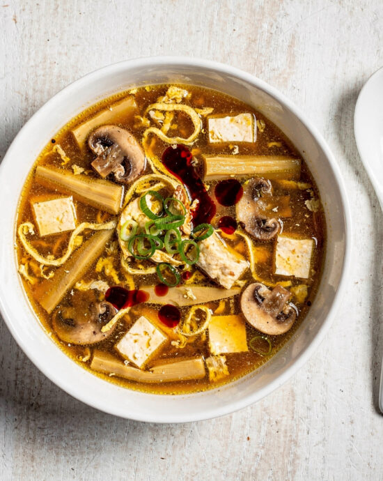 A steamy, inviting bowl of homemade hot and sour soup, filled with tofu, mushrooms, and egg ribbons.