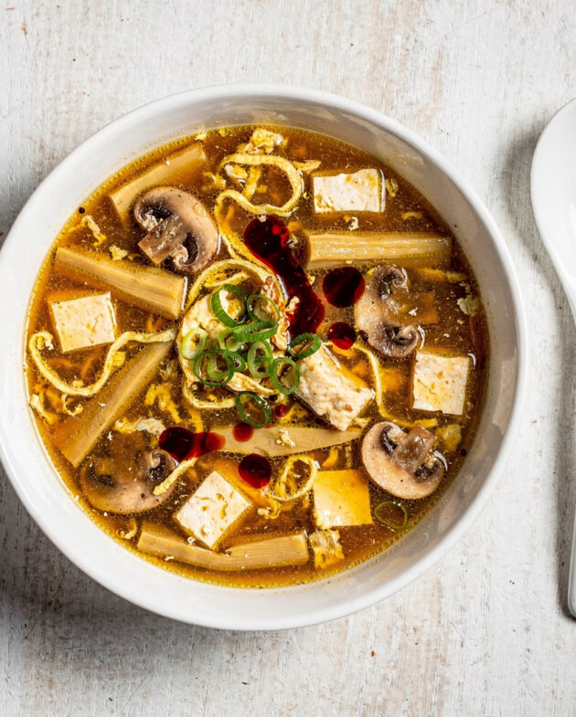A steamy, inviting bowl of homemade hot and sour soup, filled with tofu, mushrooms, and egg ribbons.