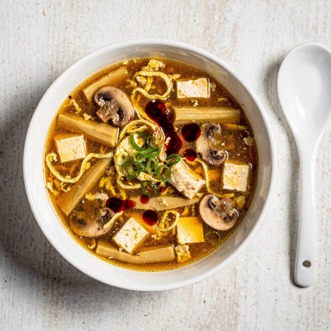 A steamy, inviting bowl of homemade hot and sour soup, filled with tofu, mushrooms, and egg ribbons.