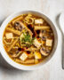 A steamy, inviting bowl of homemade hot and sour soup, filled with tofu, mushrooms, and egg ribbons.