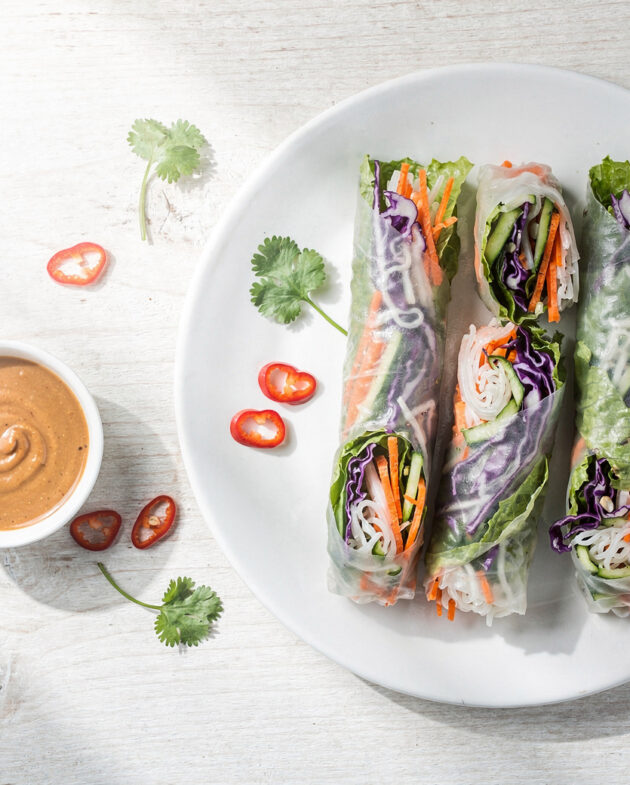 Golden, crispy spring rolls recipe served on a rustic wooden board with vibrant dipping sauce.