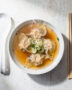 A beautifully styled bowl of our homemade wonton soup recipe, featuring plump dumplings and a clear, aromatic broth.
