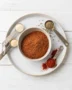 A small bowl of homemade taco seasoning with measuring spoons and spices nearby.